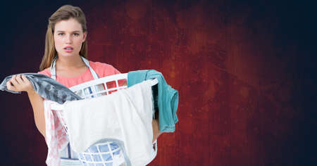 Portrait of a caucasian woman with laundry basket against copy space on textured red background. laundry conceptの写真素材