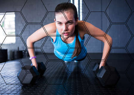 Hexagonal shapes pattern against caucasian fit woman performing push up exercise with dumbbells....