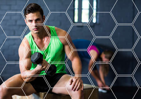 Hexagonal shapes pattern against caucasian fit man performing exercise with dumbbells at the gym....