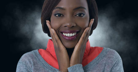 African american businesswoman smiling with hands on her chin against copy space on black...