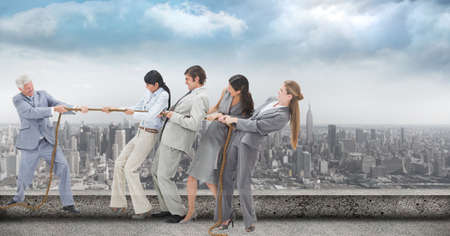 Composite image of businesspeople pulling on a rope during tug of war against view of cityscape....