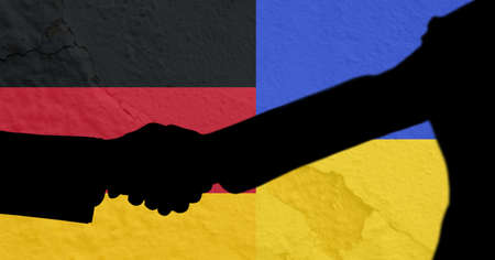 Silhouette of two men shaking hands against ukraine and germany flag background. international relations conceptの写真素材