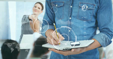 Data processing over mid section of a man writing on clipboard against businesswoman at office....