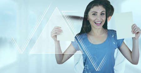 Abstract shapes over portrait of caucasian woman holding blank papers against blue background. business and technology conceptの写真素材