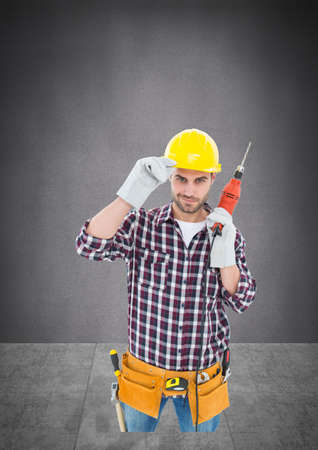 Portrait of caucasian male worker holding a drill machine against copy space on grey background. repair service conceptの写真素材