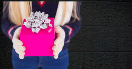 Mid section of a woman holding a gift box against against copy space on grey brick wall background. christmas festivity conceptの写真素材