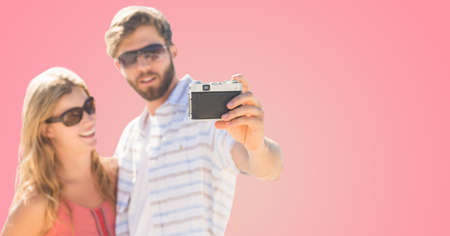 Caucasian couple taking a selfie with a digital camera against copy space on pink background. travel and vacation conceptの写真素材