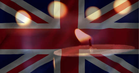 Digital composite of British flag with candles in the background. One candle going out