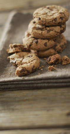 Vertical image of stack of chocolate chip cookies on cloth and wooden background. sweet foods and...