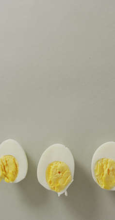 Vertical image of high angle view of two halves of hard boiled eggs with copy space on grey. easter and fresh dairy food.の写真素材