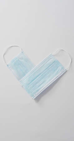 Vertical image of overhead view two face masks forming heart shape on white background. healthcare...
