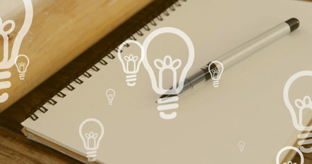 Image of lightbulb icons over notebook and pen. national writing day and celebration concept digitally generated image.の写真素材