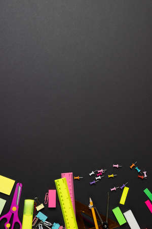 Imagine of various office supplies, pins, rulers, scissorson on black background. Education,...