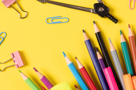 Imagine of various office supplies and plastic utensils, notebook, crayons on yellow background. Education, learning and creativity.の写真素材