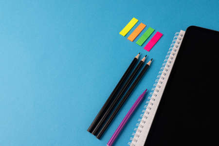 Image of various office supplies, pens and notebook on blue background. Education, learning and...