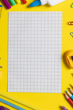 Imagine of various office supplies and plastic utensils, notebook, crayons on yellow background....