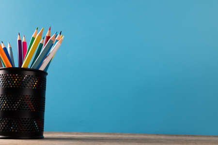 Image of cup of crayons on wooden table over blue background. Education, learning and creativity.の写真素材