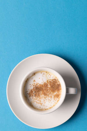 Image of white cup of coffee with milk on blue background. Coffee, refreshment and beverages.の写真素材
