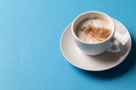 Image of white cup of coffee with milk on blue background. Coffee, refreshment and beverages.の写真素材
