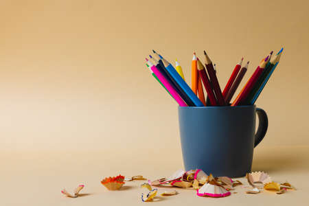 Composition of colorful crayons in blue mug on yellow surface with copy space. School equipment, drawing tools, pattern and creativity concept.の写真素材