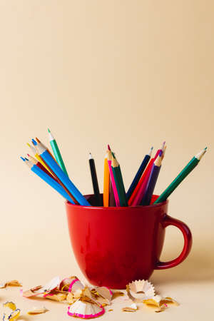 Vertical composition of colorful crayons in blue mug on yellow surface with copy space. School equipment, drawing tools, pattern and creativity concept.の写真素材