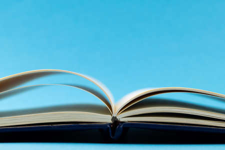 Image of open book with navy blue cover on blue background. Education, learning and creativity.の写真素材