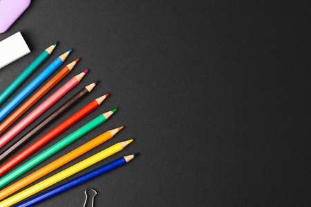 Composition of colorful crayons and school items on black surface with copy space. School equipment, drawing tools, pattern and creativity concept.の写真素材