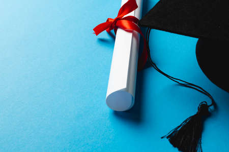Image of graduation hat and diploma on blue surface. School, learning, education and graduation...