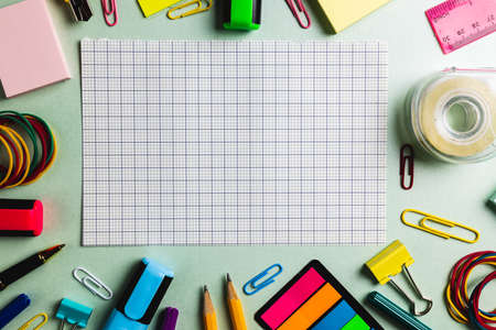 Composition of checked sheet and frame made of school tools on green surface. School equipment, tools and creativity concept.の写真素材