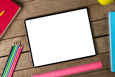 Composition of tablet with copy space and school equipment on wooden surface. School equipment,...