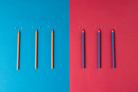 Composition of pencils with eyes on blue and pink surface. School equipment, tools, learning and creativity concept.の写真素材
