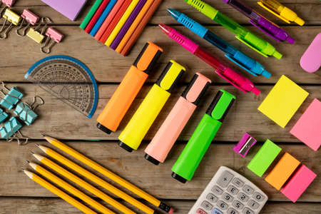 Composition of colorful crayons, pens, markers and other school tools on wooden surface. School equipment, tools, learning and creativity concept.の写真素材