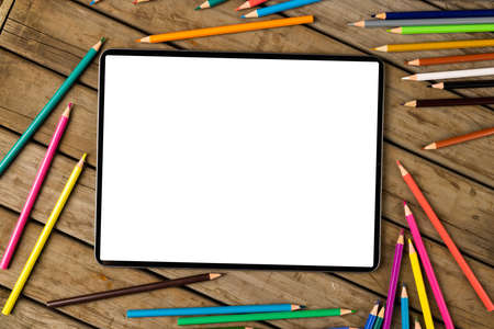 Composition of tablet with copy space and crayons on wooden surface. School equipment, tools, learning with technology and creativity concept.の写真素材