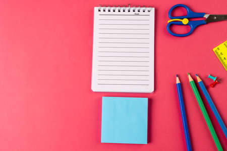 Composition of colorful school equipment with notebook and post it on blue and pink surface. School...