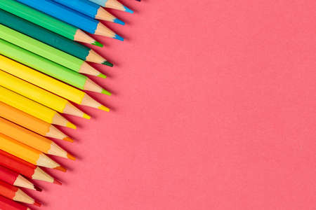 Composition of colorful crayons on pink surface with copy space. School equipment, tools, education, pattern and creativity concept.の写真素材