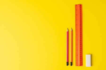 Composition of rulers, pencils and eraser on yellow surface with copy space. School equipment, tools, education and creativity concept.の写真素材