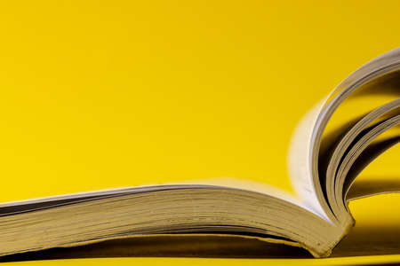 Image of open book on yellow surface with copy space. School equipment, tools, learning and education concept.の写真素材