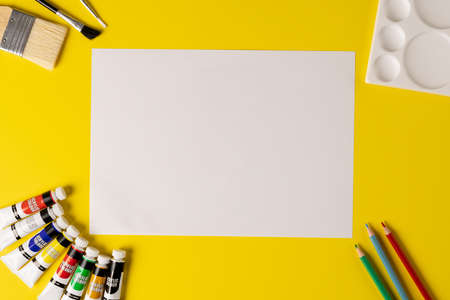 Image of blank sheet with copy space and painting tools on yellow surface. School equipment, tools, learning and education concept.の写真素材