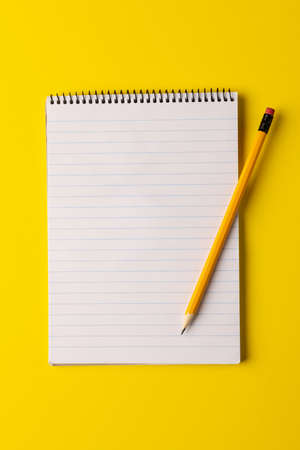 Vertical image of notebook with copy space and pencil on yellow surface. Business, working in...