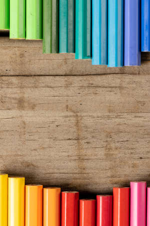 Vertical composition of colorful crayons on wooden background. School equipment, tools, education,...