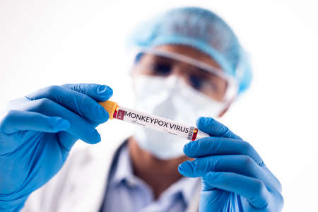 African american male doctor wearing face mask, holding vial with monkeypox virus. Monkeypox virus,...