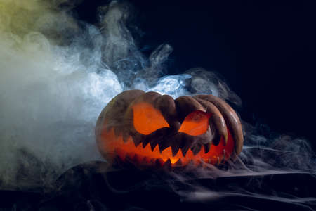 Composition of halloween carved pumpkin with smoke on black background. Halloween tradition and celebration concept.の写真素材