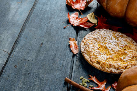 Composition of autumn leaves, pumpkins, spices and pie on wooden background. Halloween, autumn, tradition and celebration concept.の写真素材