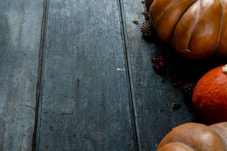 Composition of pumpkins with pinecones and rowanberries on wooden background. Halloween, autumn, tradition and celebration concept.の写真素材