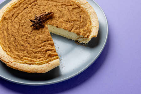Composition of pumpkin pie with spices on plate on purple background. Halloween, autumn, tradition and celebration concept.の写真素材