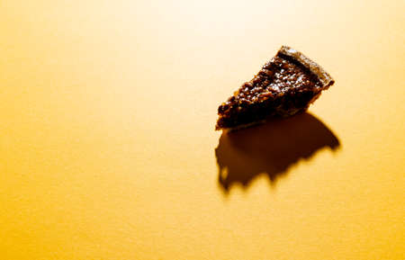 Composition of piece of pie with shadow on orange background. Halloween, autumn, tradition and celebration concept.の写真素材