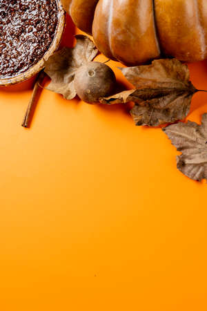 Composition of autumn leaves, pumpkinm, spices and pie on orange background. Halloween, autumn, tradition and celebration concept.の写真素材