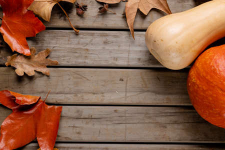 Composition of pumpkins and autumn leaves on wooden background. Halloween, autumn, tradition and...