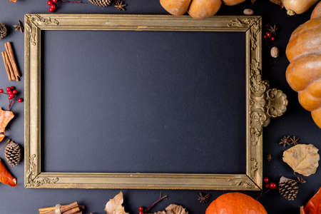 Composition of pumpkins with autumn leaves and frame with copy space on black background. Halloween,...