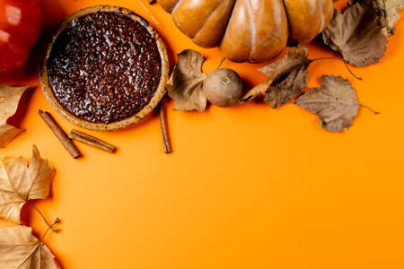 Composition of pumpkins, autumn leaves, cinnamon and pie on black background. Halloween, autumn, tradition and celebration concept.の写真素材